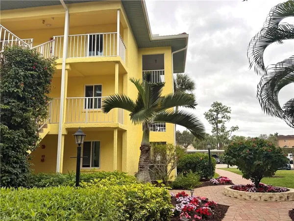 a front view of a multi story residential apartment building with yard and parking