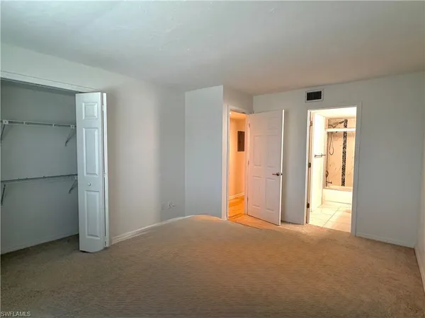 a view of an empty room with closet and a window
