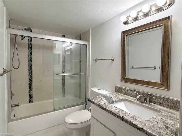 a bathroom with a granite countertop sink toilet mirror and shower