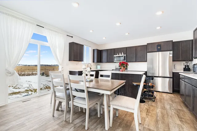 a kitchen with a dining table chairs refrigerator and microwave