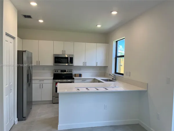 a kitchen with granite countertop a refrigerator and a stove top oven