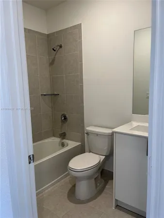 a bathroom with a granite countertop bathtub shower sink and toilet