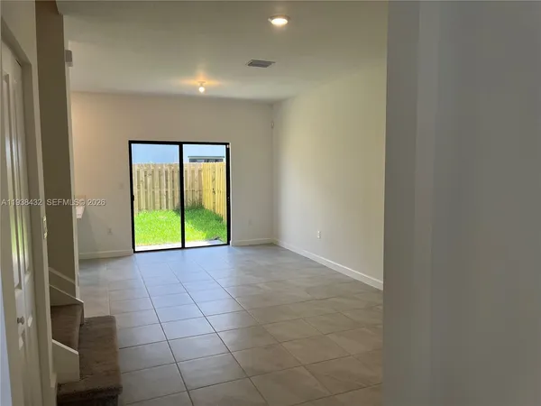 a view of an empty room with window and bathroom