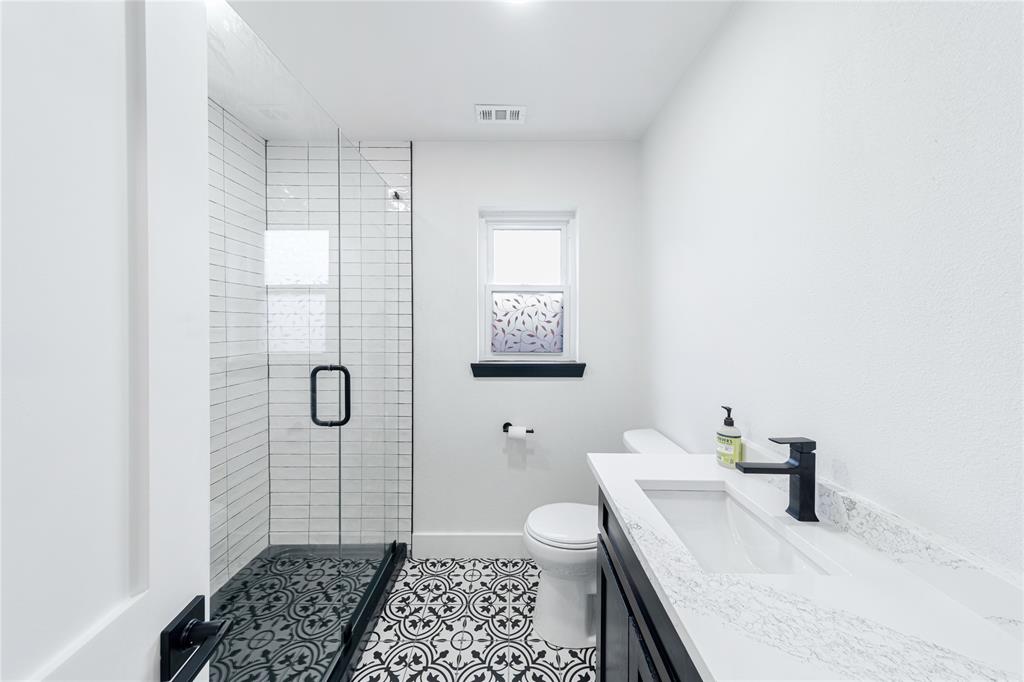 932 Treasure Road Garland, TX 75041 - Photo 17 of 23 a bathroom with a sink a toilet and shower