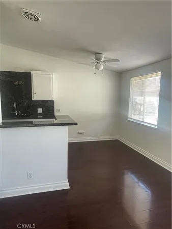 an empty room with wooden floor cabinet and a sink