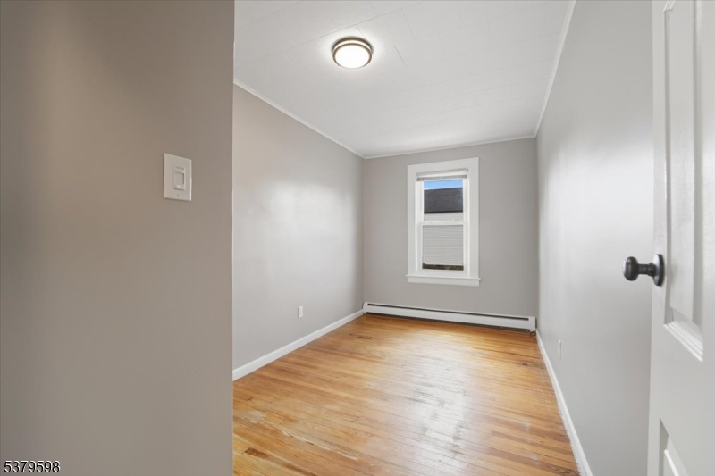 102 Exton Avenue, Unit 1 North Arlington, NJ 07031 - Photo 9 of 18 a view of an empty room with wooden floor and a window