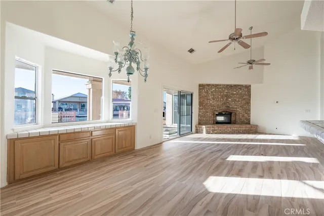 a view of an empty room with window wooden floor and a kitchen view
