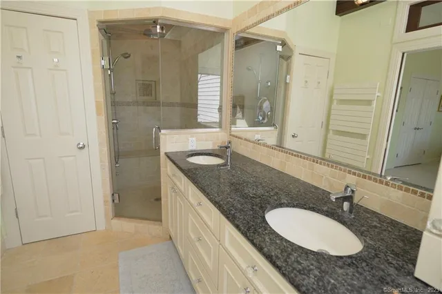 a bathroom with a granite countertop double vanity sink and mirror
