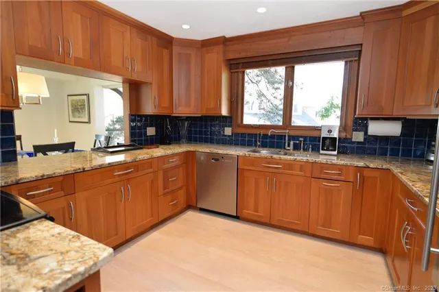 a kitchen with stainless steel appliances granite countertop wooden cabinets a sink and a large window