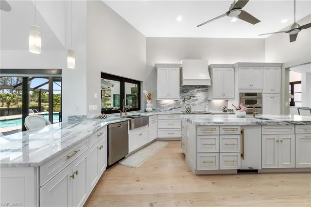 a large white kitchen with granite countertop a sink window and cabinets