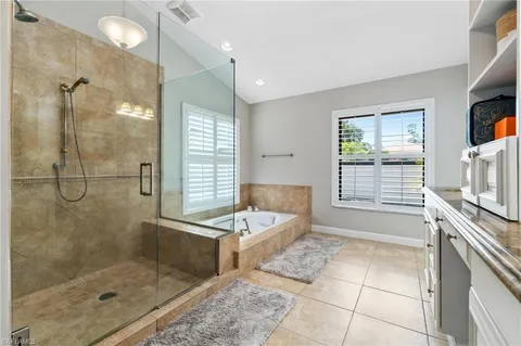 a bathroom with a tub a sink a mirror and a shower