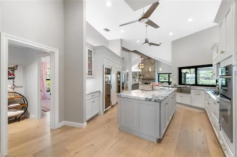 a large kitchen with stainless steel appliances kitchen island granite countertop a large counter top and a view of living room