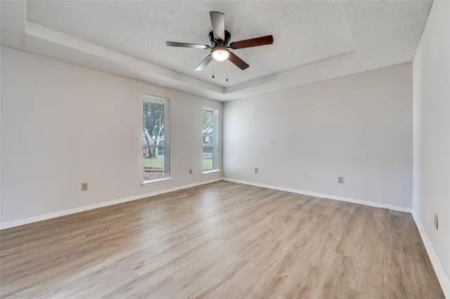 an empty room with wooden floor and ceiling fan
