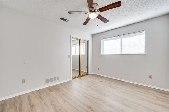 an empty room with wooden floor ceiling fan and windows