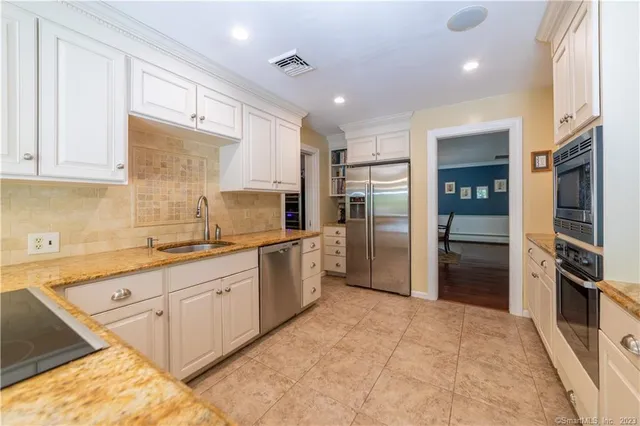 a large kitchen with stainless steel appliances granite countertop a refrigerator and a sink