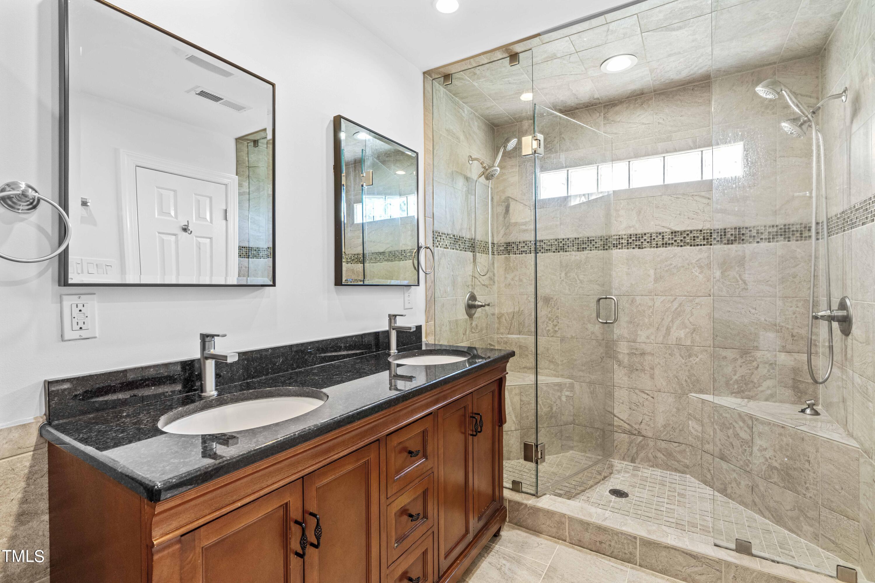1206 Rainesview Lane Apex, NC 27502 - Photo 15 of 26 a bathroom with a granite countertop sink a mirror a shower and a bathtub