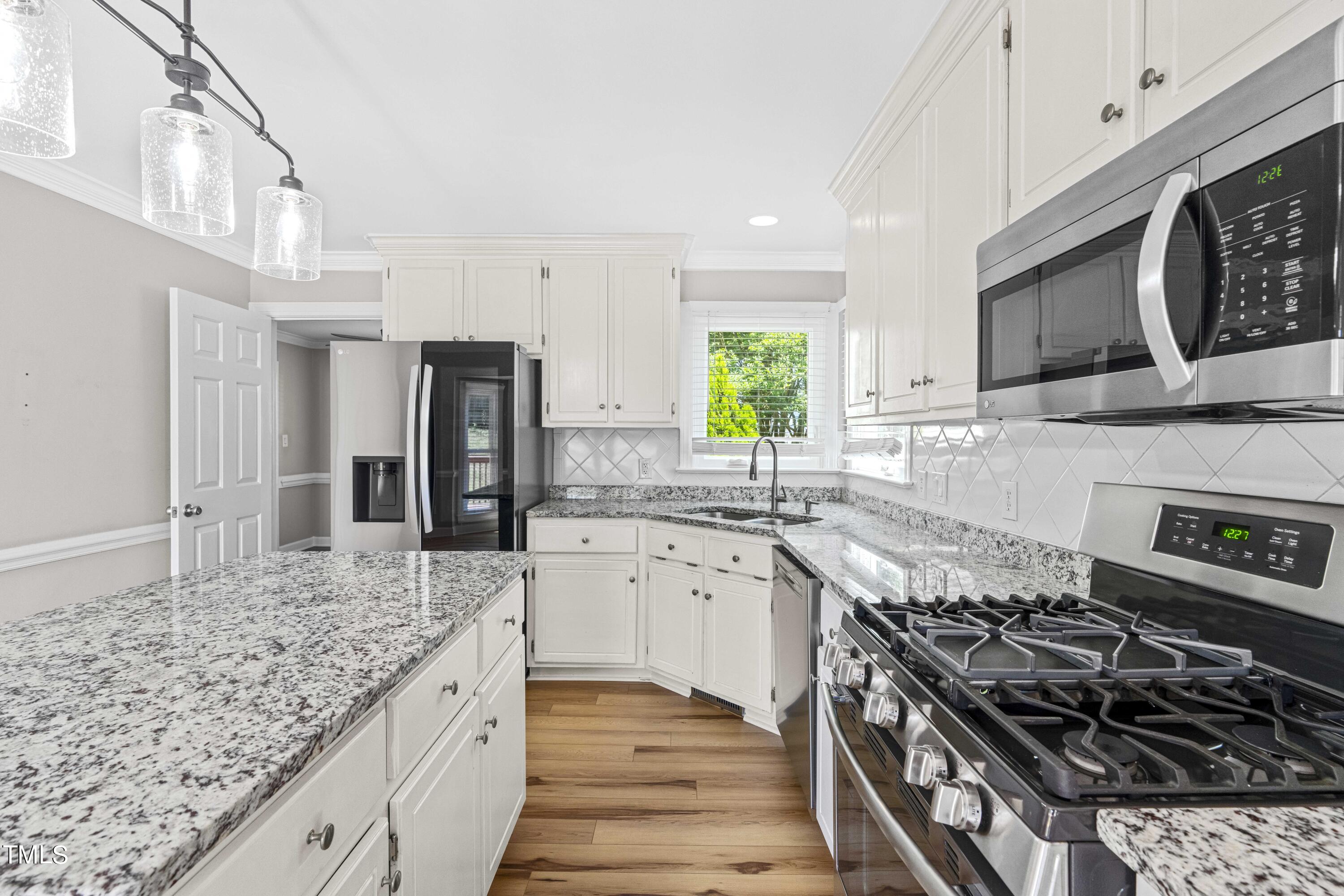 1206 Rainesview Lane Apex, NC 27502 - Photo 4 of 26 a kitchen with stainless steel appliances granite countertop a stove a sink and a microwave