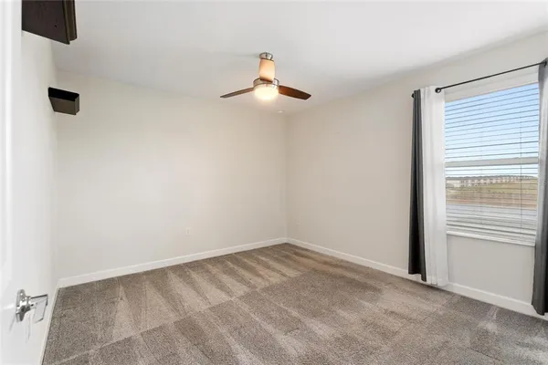 an empty room with a ceiling fan and a window