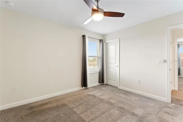 an empty room with chandelier fan and windows
