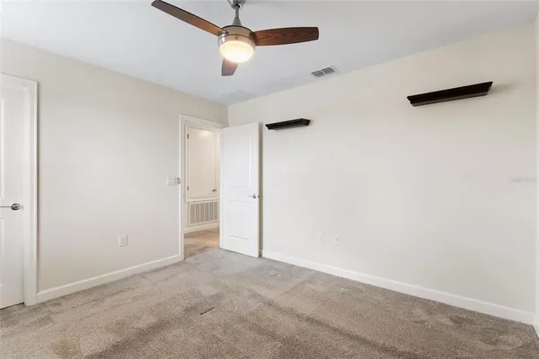 an empty room with ceiling fan and window