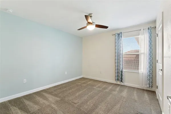 an empty room with ceiling fan and window