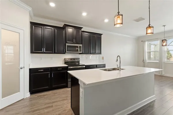 a kitchen with stainless steel appliances granite countertop a sink a stove top oven a refrigerator with grey cabinets