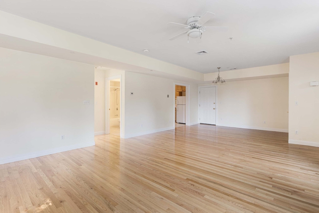 756 Washington Street, Unit A Canton, MA 02021 - Photo 5 of 20 an empty room with wooden floor and ceiling fan