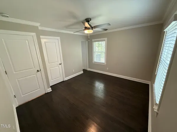 an empty room with wooden floor cabinet and windows