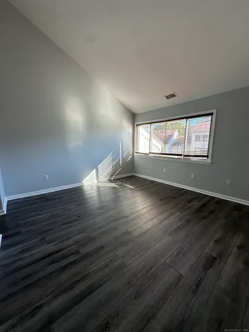 a view of a hallway with wooden floor and a bathroom