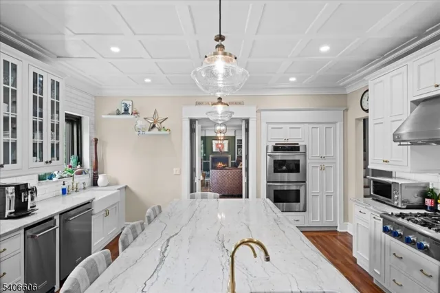 a kitchen with stainless steel appliances kitchen island granite countertop a refrigerator oven a sink dishwasher and a stove with wooden floor