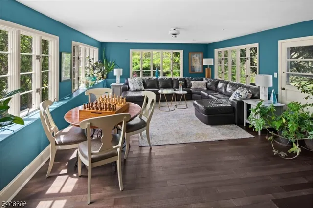 a living room with furniture potted plant floor to ceiling windows and a flat screen tv
