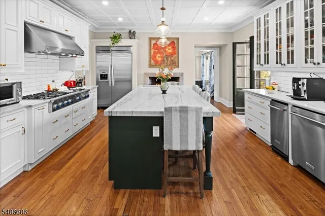 a kitchen with granite countertop a stove a sink dishwasher and a refrigerator with wooden floor