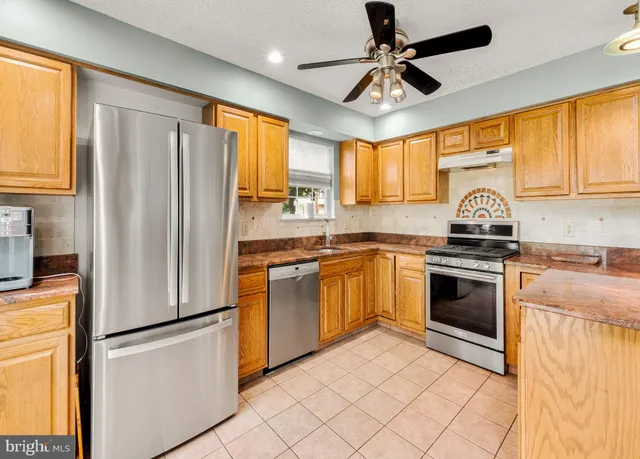 a kitchen with granite countertop stainless steel appliances a refrigerator cabinets and a window