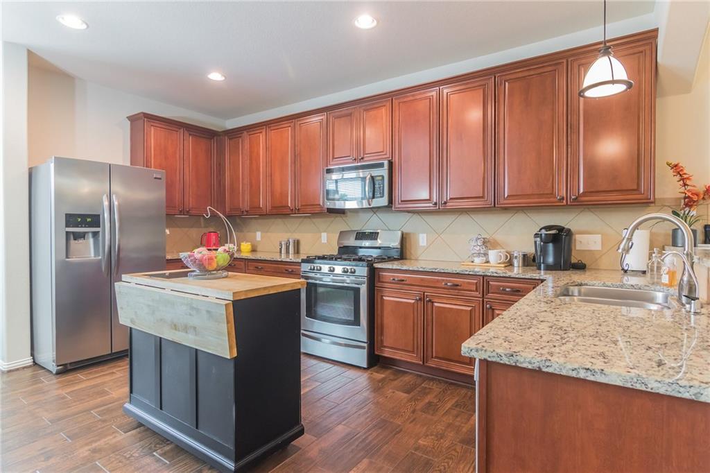 252 Pond View Pass Buda, TX 78610 - Photo 6 of 37 Kitchen with stainless steel appliances, light stone countertops, dark wood-style floors, hanging light fixtures, and a center island
