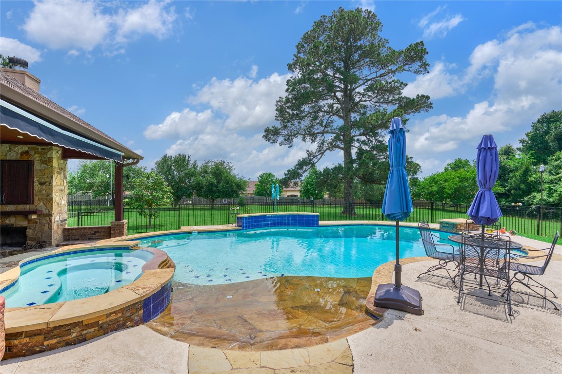 19089 Grandview Point Montgomery, TX 77356 - Photo 2 of 48 This stunning property features a spacious, inviting pool with elegant stone accents and a serene waterfall. The backyard offers a beautifully landscaped, fenced-in area with lush greenery, perfect for relaxation and entertaining.
