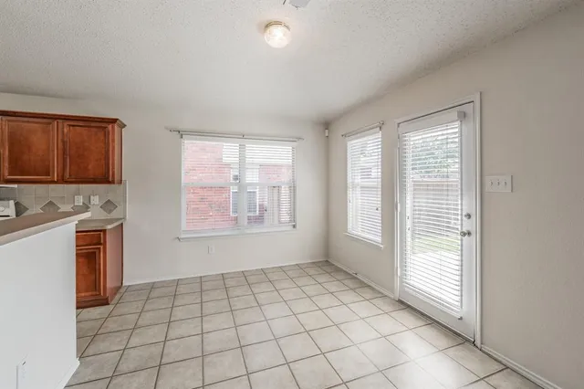 a view of an empty room with a window and a kitchen
