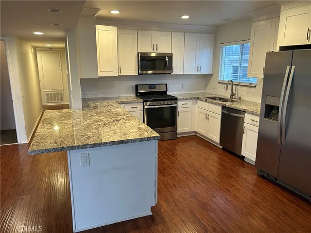 a kitchen with granite countertop a refrigerator and a stove top oven
