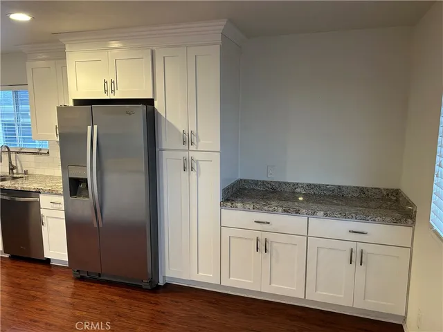 a kitchen with granite countertop a refrigerator sink and cabinets