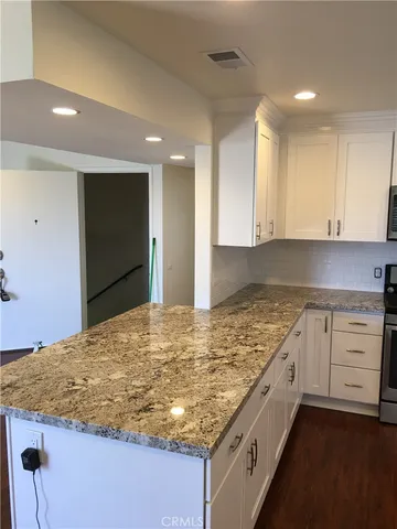 a kitchen with kitchen island granite countertop a sink and white cabinets