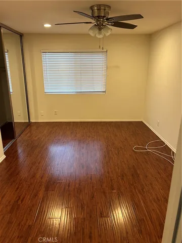 an empty room with wooden floor fan and windows