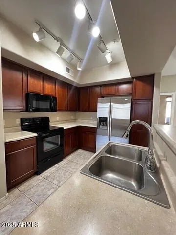 a kitchen with stainless steel appliances granite countertop a sink a stove and a microwave oven with cabinets