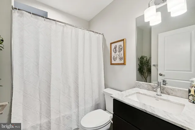 a bathroom with a granite countertop sink vanity mirror and toilet