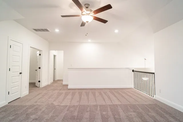 an empty room with ceiling fan and windows