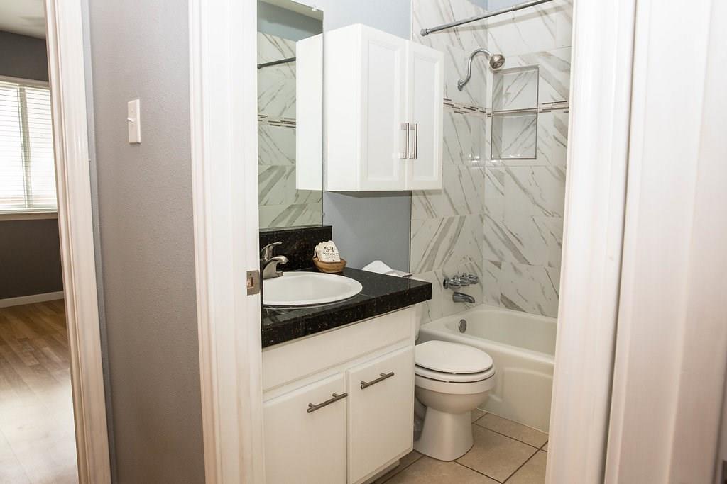 4209 Burnet Road, Unit 206 Austin, TX 78756 - Photo 12 of 20 Granite counters and tiled shower enclosure add a luxurious touch to this primary bathroom.
