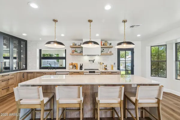 a kitchen with stainless steel appliances a dining table chairs and stove top oven