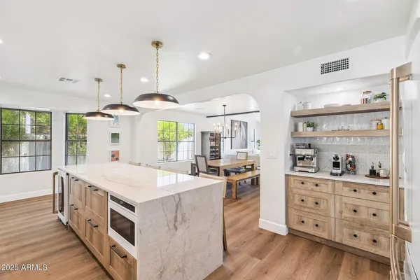 a large kitchen with kitchen island a stove a wooden floor and a large window