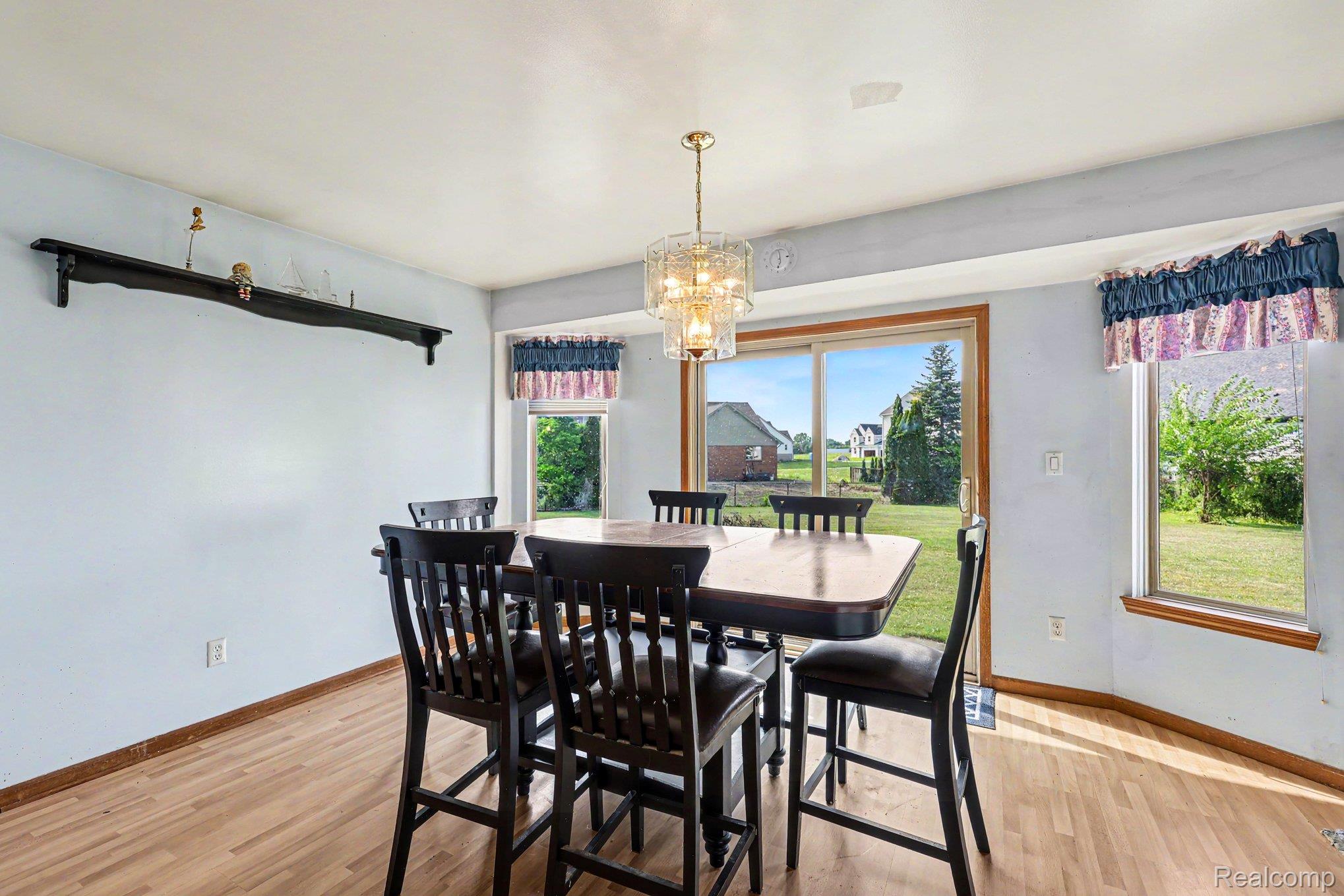 28355 Gamble Road New Baltimore, MI 48047 - Photo 7 of 18 Wood-finish flooring, built-in wall shelf, large sliding glass door, and an ornate chandelier