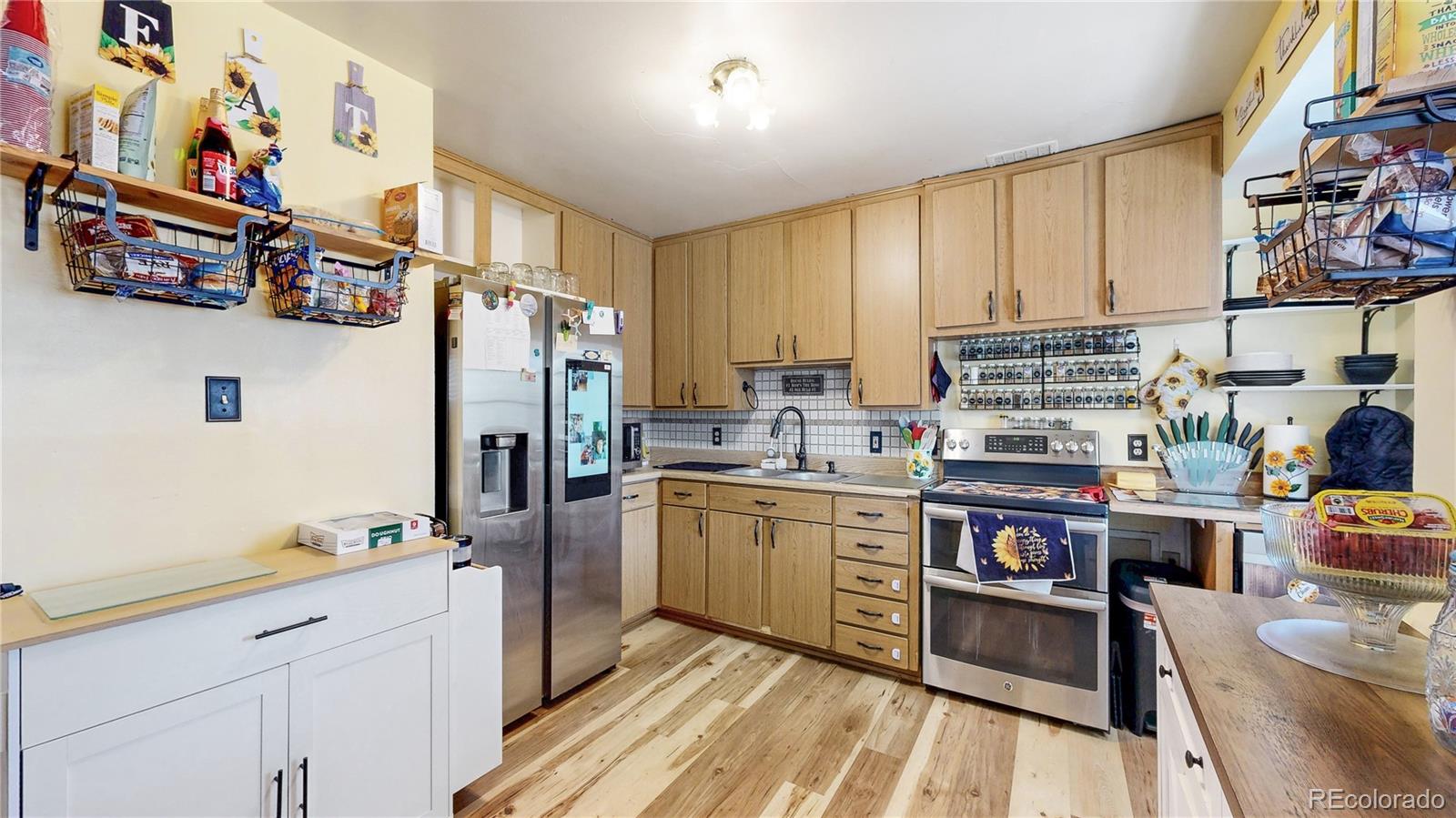 1960 Rowena Street Thornton, CO 80229 - Photo 10 of 48 a kitchen with stainless steel appliances granite countertop a refrigerator and a stove top oven