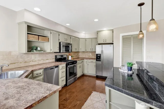 a kitchen with granite countertop a sink a counter top space appliances and cabinets