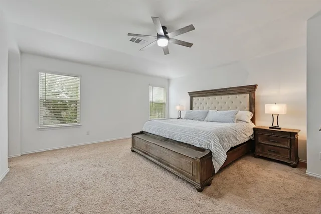 a spacious bedroom with a bed and a ceiling fan